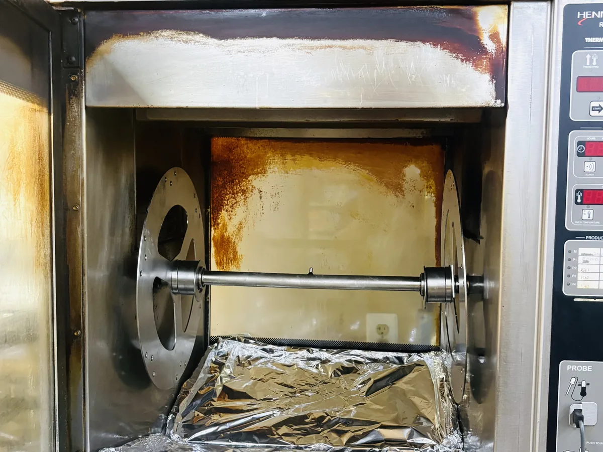 Rotisserie oven interior coated in carbonised grease before cleaning