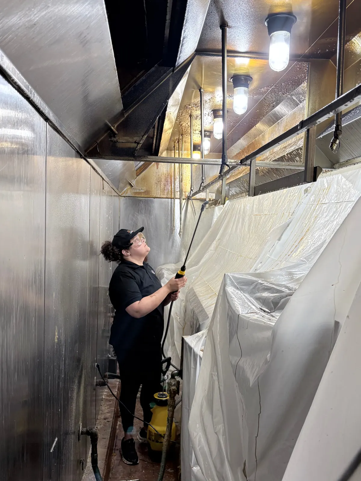 ARC technician in PPE cleaning a stainless steel kitchen hood
